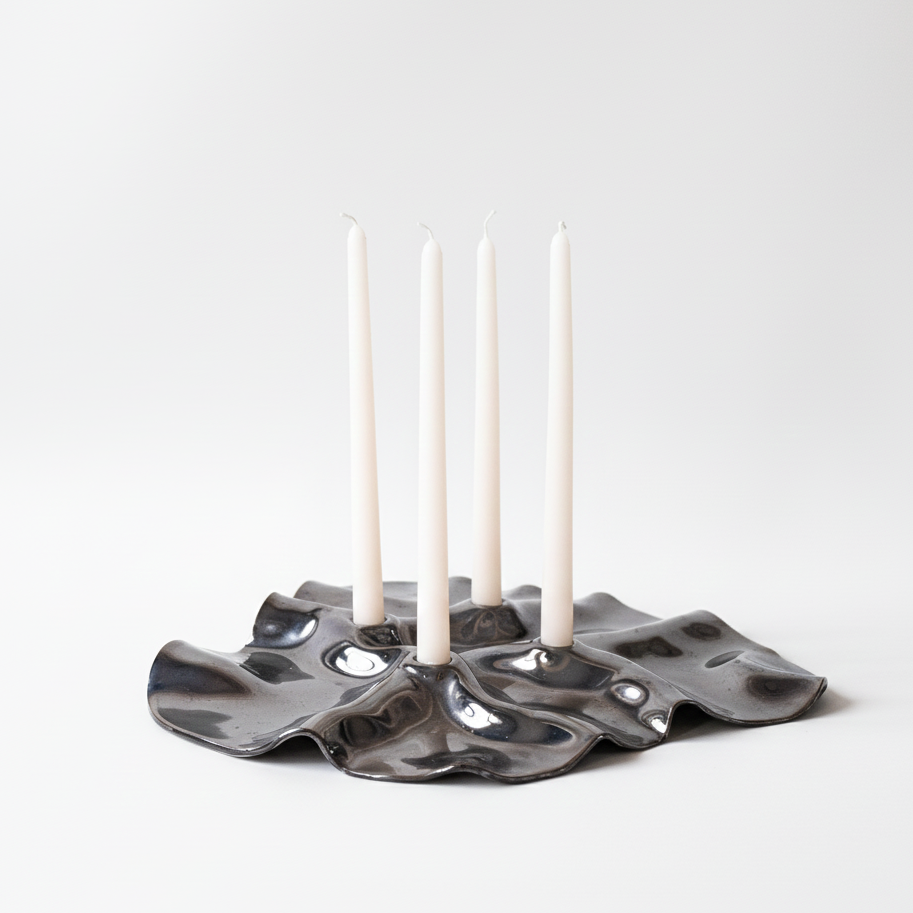 Ceramic candle holder with four white candles on a white background