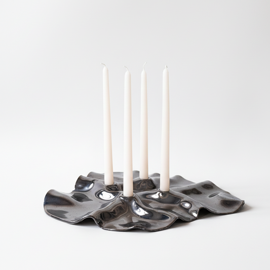 Ceramic candle holder with four white candles on a white background