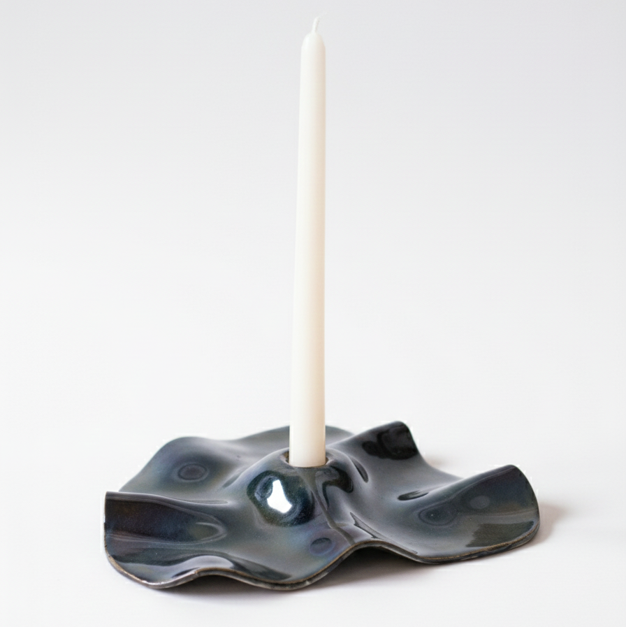 Ceramic candle holder with a white candle on a light gray background