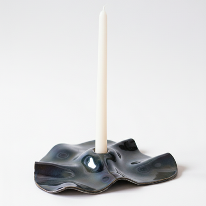 Ceramic candle holder with a white candle on a light gray background