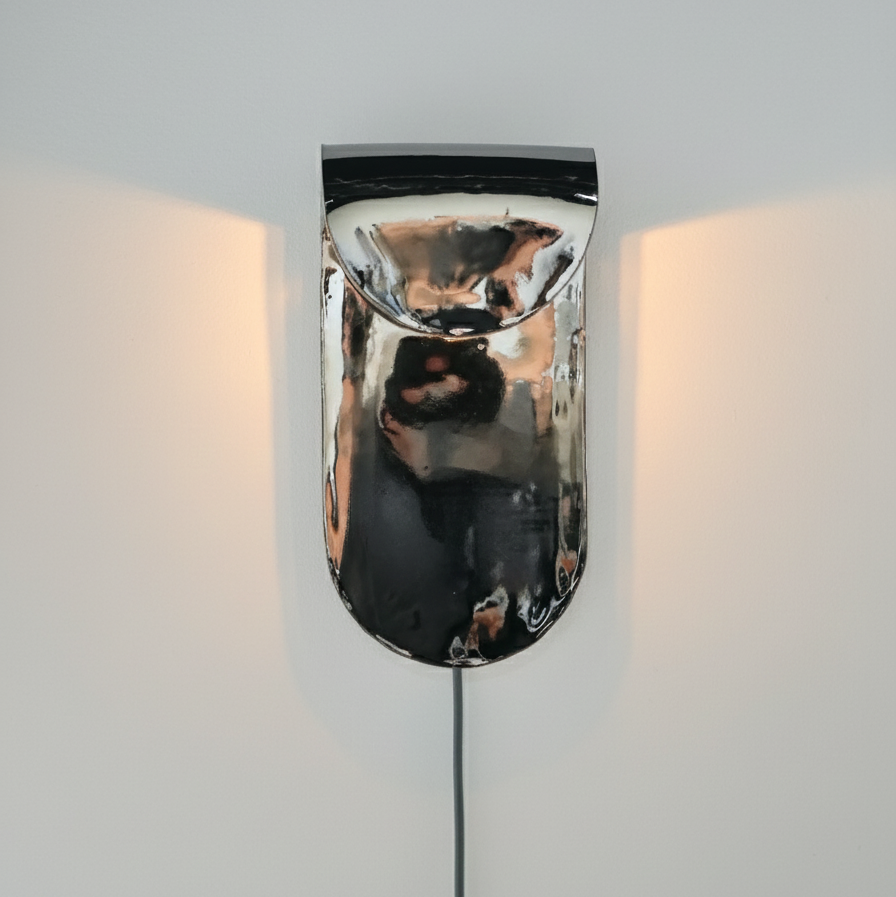 Wall-mounted light fixture with a metallic finish on a plain background