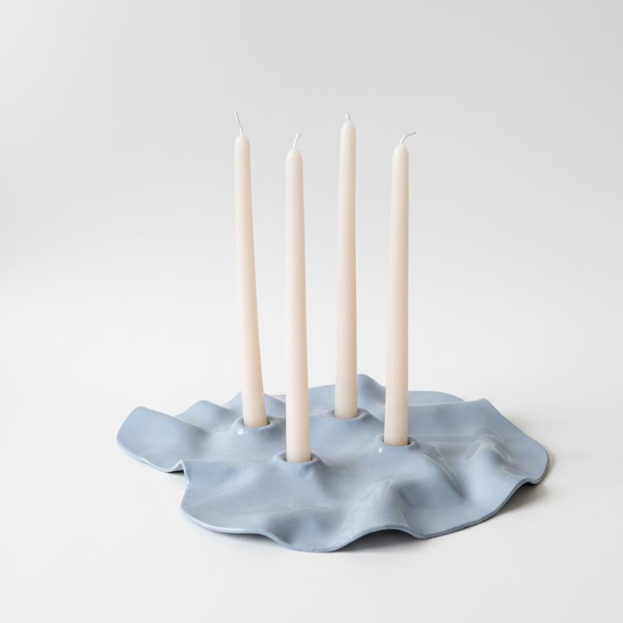 Blue ceramic candle holder with four white candles on a light gray background